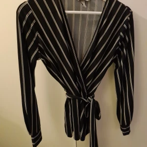 V ringad randig topp Strl S - Vringad randig topp från H&M med knytband i höften. Passar en S-M! Går att ta loss bandet om man vill det! Säljer endast pga att den är lite väl vringad för mig med små bröst som inte håller den uppe 😅✌🏻