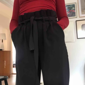  - Raka byxor ifrån Bik bok. Gylf med knytbälte över. Hög midja med olika vikningar som blir snyggt längst med midjan. En liten fläck på bältet men syns knappt, men visade upp det på bilden. 