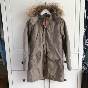 Höst-/vinterjacka - Beige höst/vinterjacka med pälskrage (går att ta av). I riktigt bra skick. Säljer pga av för liten för mig. Köparen står för frakt, kan även mötas upp i Helsingborg.  