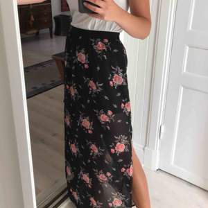 Trendig lång svart kjol med stora blommor/rosor och slits. Ca 37 cm lång. Skön kjol med resor i midjan. Funkar perfekt både till stranden och i stan!🌞 Aldrig använd. 