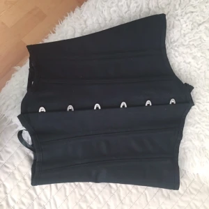  - Svart midjekorsett i denimmaterial med 26 metallspiralfjädrar och metallskenor runt om, planchettknäppning fram och snörning bak.

Korsetten passar perfekt pga dessa fjädrar och skenor för midjeträning samt att den även har kraftfull snörning baktill. 

Tillverkad av 90 % polyester och 10 % spandex

Kan användas som midjeträning!

Storlek S

helt oanvänd endast testad och har lappar kvar!