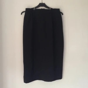  - Svart pennkjol med hög midja. Second hand/vintage. Stänges med dragkedja och knapp bak. Liten slits mitt bak i nederkant. Frakt tillkommer.