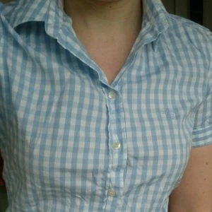  - Kortärmad rutig skjorta från Gant. Använd några få gånger så är i bra skick och fräsch. Ljusblå och vit. Stretchig i modellen. 97% bomull, 3% elastan. Passar 38-40 Nypris: 899kr 