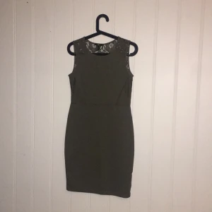  - Militärgrön klänning med spetsdetaljer på sidorna och i ryggen. Aldrig använd. 