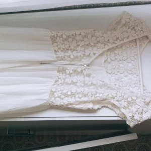  - Vit klänning i blommönstrad spets. Aldrig använd. Sitter som en stl 38.