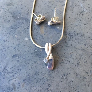  - Halsband i silver med Cubik zirkonia-kristall. Matchande örhängen. Knappt använda.  30 kr för halsbandet och 30 kr för örhängena. 50 kr vid köp av båda.  Frakt 7 kr.  Betalning via swish, kontoinbetalning eller via Plick.  Kolla gärna in mina andra annonser också. Jag säljer smycken, väskor, sjalar, kläder och skor. Kan samfrakta. 