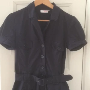  - Marinblå skjortklänning ifrån MQ, märke Zoul. Passar även 36a eftersom den är liten i storleken. Skärp i midjan och liten puffärm. Lite rynkig på kortet då den legat nerpackad. Den har dessvärre blivit liten för mig. Fint skick. Frakt tillkommer. 