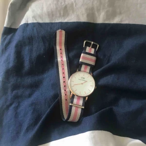  - DW klocka i mycket fint skick! Klockan är i rosé guld och bandet är blå, vit, rosa randigt. Används tyvärr inte längre