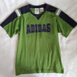  - Vintage grön Adidas t-shirt i fint skick. Står storlek 164 på lappen men är som ca storlek S/M. Kan skickas om köparen står för fraktkostnaden som blir 36kr. 