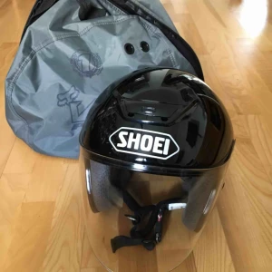  - MC-Hjälm Shoei J-Wing Plain svart  CE-godkänd E22:05. Hakspänne med dubbla D-ringar. Klart imfritt pinlockvisir (CJ-1) som låses i stängt läge för att inte vibrera i höga farter.  VIKT: 1290 +/- 50 gr i stlk L  Väska till 