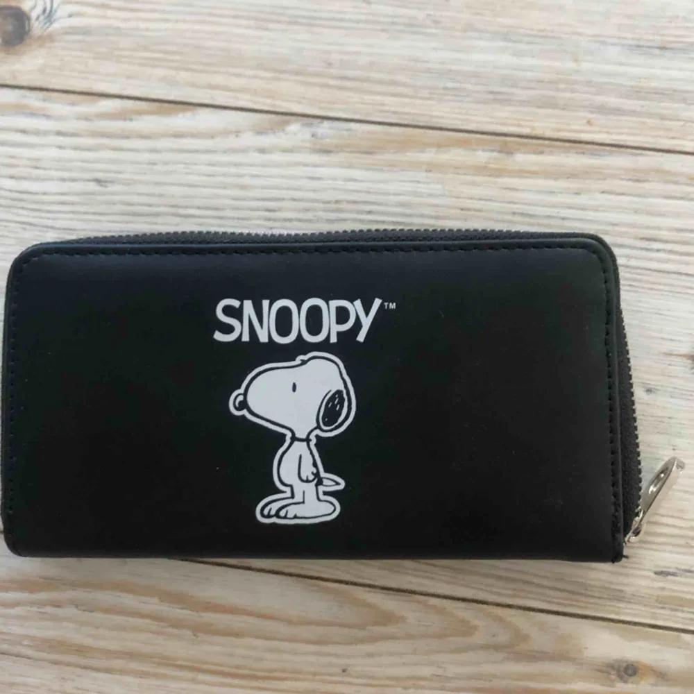 En ganska stor plånbok med ett motiv på Snoopy.. Accessoarer.