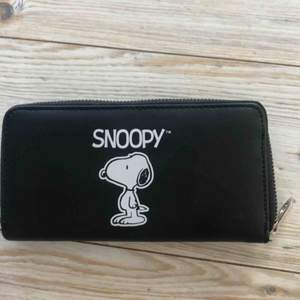 En ganska stor plånbok med ett motiv på Snoopy.