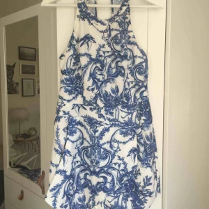 - Helt ny jumpsuit (prislapp sitter kvar) från märket Xenia i Australien. Vit/blå med blommigt mönster. Halterneck-modell med öppen rygg. Nypris ca 450 kr. Storlek L/UK 12. Hämtas i Malmö alternativt står köparen för frakt.