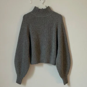 Stickad tröja - Väldigt mjuk och varm stickad tröja från H&M! Nyskick, endast använd 2ggr! Hög krage, lite ballongärmar och längre muddar gör den väldigt mysig! Materialet är ullmix. Nypris 299kr