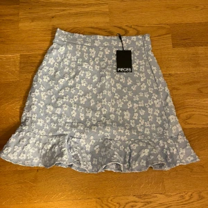 Kjol - En blå kjol med blommor från vero Moda. Helt oanvänd då den inte kommit till användning. Lappen är kvar. Pris kan diskuteras