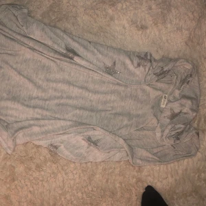 Kofta med sjärnor  - En vit kofta med gråa sjärnor och en luva inga fickor