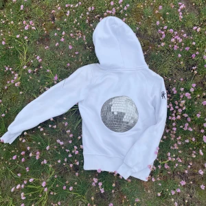 Bekväm huvtröja med snygg passform som har en discokula som tryck på baksidan.  - Secondhand huvtröja med ett eget designad tryck av DK Divine UF