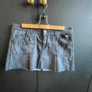 Lågmidjad jeans kjol med volanger  - Säljer denna jätte fina vintage mörkgråa jeanskjol med volanger, perfekt till sommaren. Storleken står inte men jag skulle gissa på mellan M-L/38-40, dock är den väldigt lätt att sy in i midjan om det så skulle behövas💓