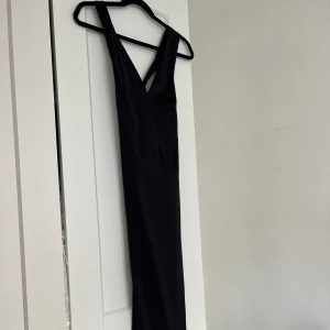 Jättefin svart klänning i en silkesmix - Klänning med lapp kvar från H&M:S premium kollektion med halterneck urringning och en halvt öppen rygg. Testad men aldrig använd. Storlek 34. I en silkemix med 