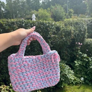 Handgjord väska - Virkad väska som jag gjort själv. Gjord i återvunnet garn.  Väskan är ca 28 cm bred och ca 18 cm djup, bandet är ca 27 cm långt🩵🩷  300kr + fraktkostnad 