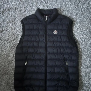 Moncler väst - Säljer min Moncler väst då jag inte har någon användning av den , pris kan diskuteras, västen är i ny skick, finns inga skador eller fläckar Qr koden finns och den funkar bra , hör av dig vid minsta lilla fundering.