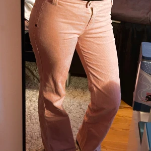 Rosa manchesterbyxor från United Colors of Benetton - Säljer ett par snygga rosa manchesterbyxor från United Colors of Benetton. Byxorna är lågmidjade och har en bootcut-stil som ger en retro vibe. De är i bra skick och perfekta för höst och vår. Byxorna har knappar och dragkedja framtill.