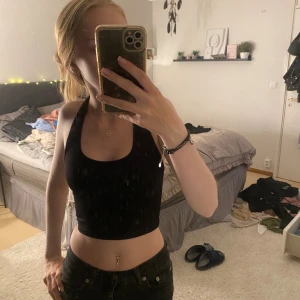 Svart croppad linne - Säljer en svart croppad linne som är perfekt för sommaren. Den är ärmlös och har en tight passform. Superbekväm och stilren, passar både till vardags och fest!