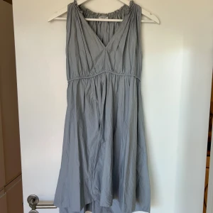 Kort klänning Hunkydory  - Kort blå/grå klänning från Hunkydory i stl S. Knytning i ryggen, alternativt att man knyter framtill då snörena är ganska långa. 100% bomull. Fint skick.