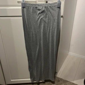 Grå långkjol från PrettyLittleThing - En enkel och stilren grå långkjol från PrettyLittleThing. Kjolen har en elastisk midja för en bekväm passform.