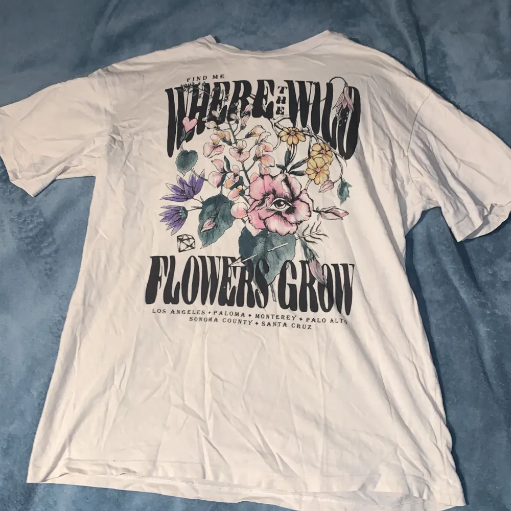 Säljer en beige t-shirt med ett coolt blommigt tryck och texten 'Find me where the wild flowers grow'. Den är i storlek Xs. Perfekt för en avslappnad och stilren look. Passar bra till både jeans och shorts!. T-shirts.