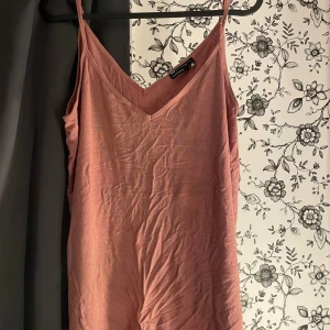 Rosa klänning med smala axelband - Säljer ett söt rosa linne med smala axelband. Har en v-ringad hals. Perfekt för sommaren, Materialet känns mjukt och bekvämt.