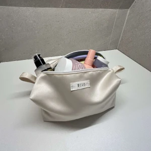 Necessär- Aten - Vit/beige satin necessär med ljusblå insida. Gjorda av återvunna textilier och är tvättbara!🥂🤍