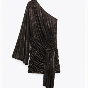 Klänning zara - Så snygg nyårsklänning från zara. Oneshoulder med knytdetalj. Färgen på känningen är brun/svart med guldskimer. Helt ny med prislapp kvar. I storlek XS.