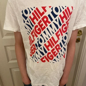 Tommy Hilfiger T-Shirt - Kolla hit! Nu säljer vi en Tommy Hilfiger T-shirt! OBS: T-shortsen har svagt bruna fläckar precis under textens högra hörn, se på bild två. 