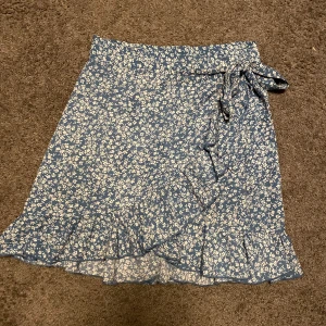 Blå blommig kjol - Fin kjol från SHEIN. Använd fåtal gånger därav bra skick. Storlek xs