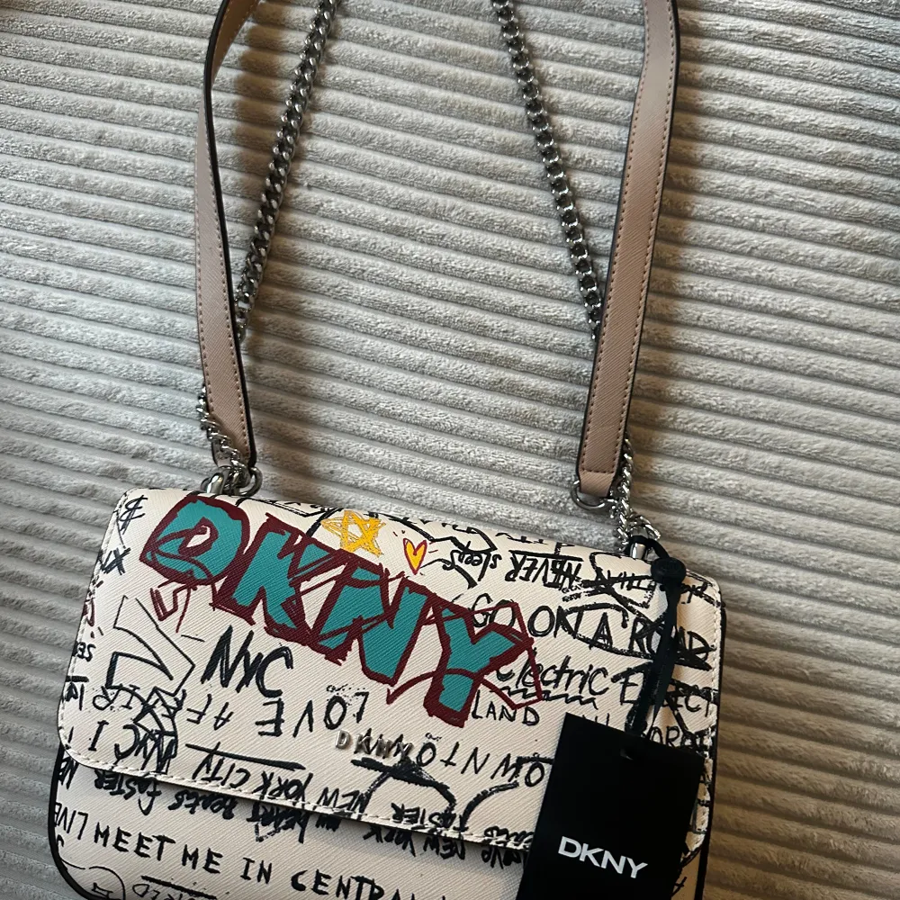 Jag säljer en helt ny DKNY axelremsväska! Den har fortfarande prislappen kvar och är modern och häftig. Den rymmer mycket och finns i Huddinge, men kan även skickas per post (köparen står för frakten). Jag köpte den för 158 dollar.. Väskor.