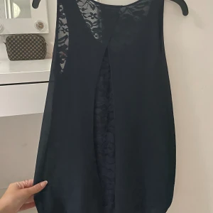 SPETS LINNE - Jätte fin topp med spets detaljerat mönster på ryggen. Toppen har varit liggandes i garderoben länge och inte kommit till användning. Marinblå/svart.