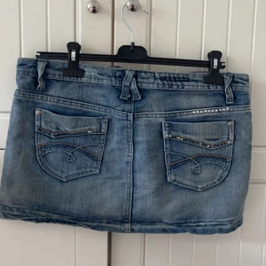 Kort jeanskjol - Säljer denna korta jeanskjolen som jag köpte för ca 1 månad sen i Kreta då den inte kommer till användning. Köpt på en marknad, men märket är ”True Z” den är i size 12, ungefär storlek M. Bredd: ca 44 cm, höjd ca 31 cm. Inga defekter!