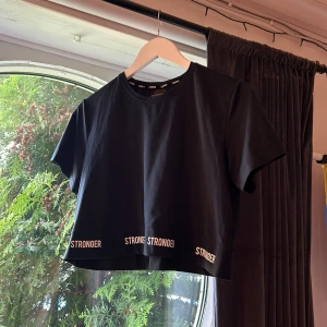 Stronger topp - Säljer en t-shirt från stronger som nästan aldrig är använd. Den är kort och lös i modellen.