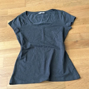 Grå tight t-shirt - Aldrig använd eftersom den var köpt i fel storlek. Ganska öppen krage. Bra kondition.