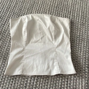 Vit topp utan band - Vit korset liknade topp med dragkedja💕väldigt söt och sitter jätte bra på❤️kan tyvärr inte ha den längre💕perfekt på sommaren💕