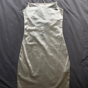 Klänning - Vit glansig och ganska kort klänning. Använd ett fåtal gånger. Något som har hänt på kanten (se bild 3) och säljer därför billigt.