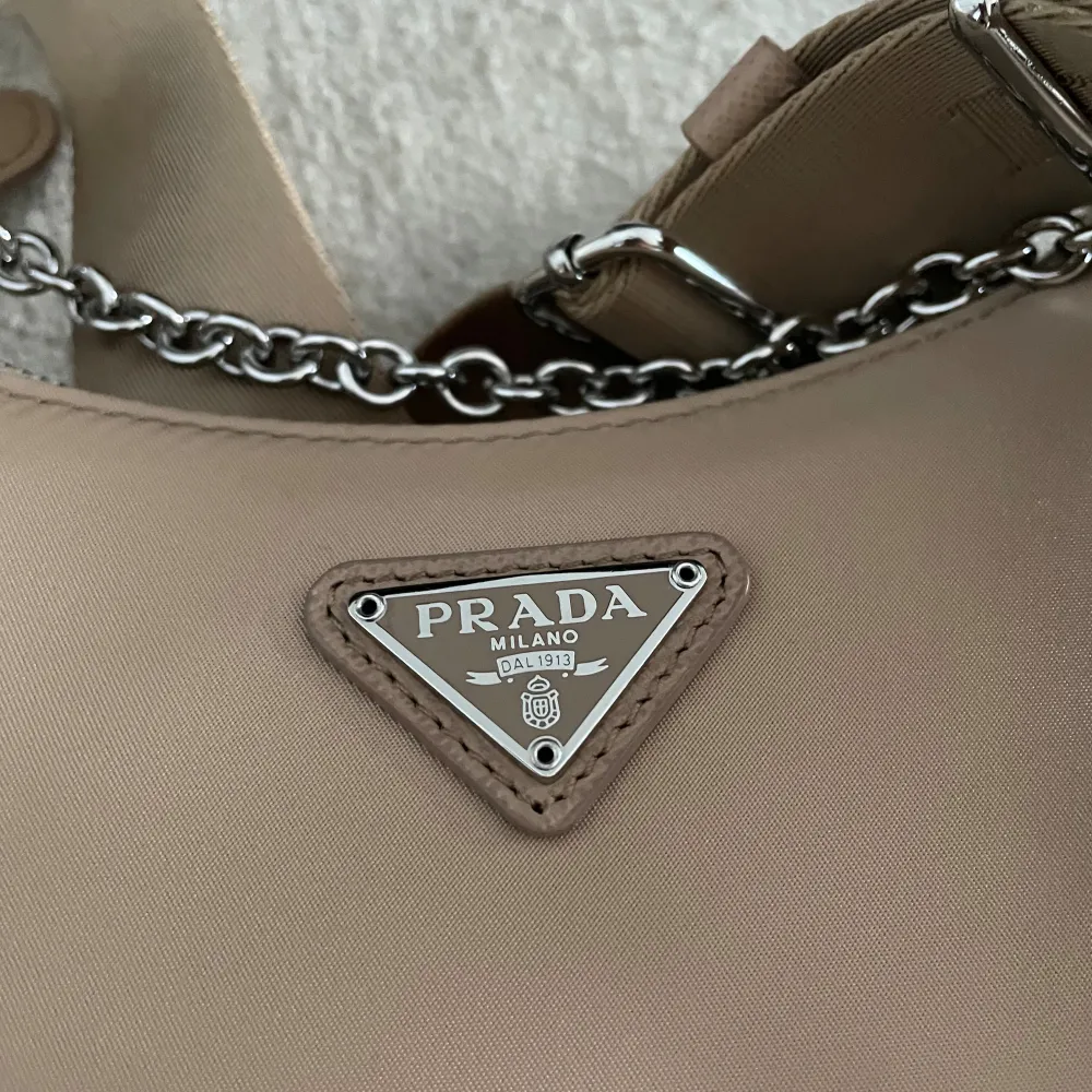 Beige Prada Re-Edition. Toppkopia köpt i Dubai för 5000kr, väskan är oanvänd och jag ser absolut ingen skillnad på min riktiga i svart och denna. Till och med kedjan har samma tyngd. Priset gäller endast vid snabb affär oh köp via Plick.. Väskor.