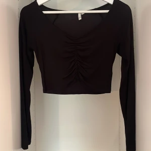 Svart topp - En svart topp med scrunch i mitten av tröjan. Är från Nelly och använd fåtal gånger. Har inga defekter.