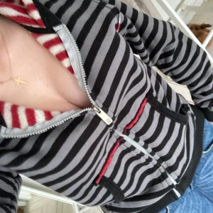 Snygg randig zipup! - Snygg randig zipup jag köpt på secondhand ❣️Grå och svart på utsidan, röd och vit på insidan! Storlek 42, skulle säga mer någonstans mellan S-M! Inga defekter förutom nån liten tråd här och där! Säljer då den inte kommer till användning ❣️