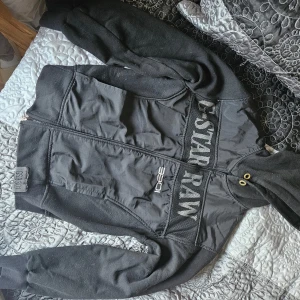 Svart jacka från G-Star RAW - En svart jacka från G-Star RAW med dragkedja framtill och ribbstickade muddar vid ärmslut och nederkant. Jackan har en normal passform och är tillverkad i ett bomullsmaterial. Lite noppig och snöret saknas till luvan, går rakhyvla bort noppriga säkert.