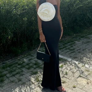 Svart klänning med vit blomma 🤍 - Svart klänning med vit blomma. Lite stretchigt material. Figursydd. Storlek 34 (insydd 36). 