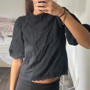 Svart blus med spetsdetaljer - En superfin svart blus med puffärmar samt broderier på framsidan och vid halsen❣️
