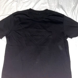 Prada t-shirt - En helt ny svart prada t shirt som har användts endast 2 gånger, den säljs då den inte riktigt är min stil, hör av dig kring funderingar 