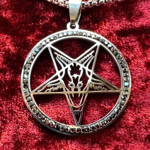 Nytt halsband Pentagram Baphomet Satanic Ockult Wicca Stainless Metal Goth Rock Punk Emo Alternativ - Nytt silverfärgat halsband i rostfritt stål och kristaller med amulett med pentagram med Baphomet. Ibland kallad bockguden från Mendez. Kristaller pryder cirkeln runt pentagrammet.   Amuletten är 4,5 x 3,5 cm. Halsbandet är 50 cm långt. Hummerlås.